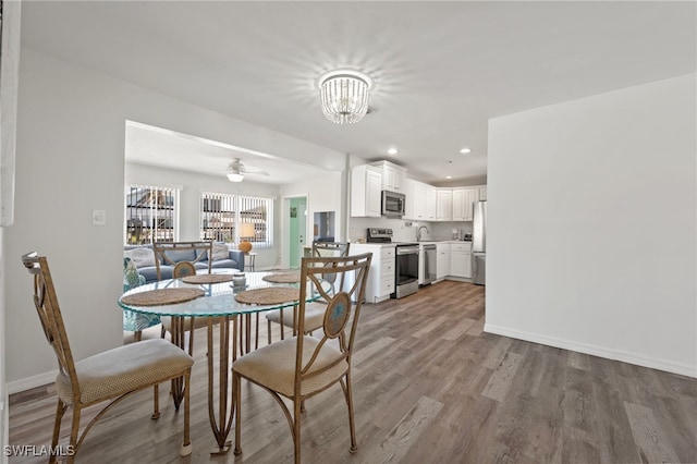 dining room featuring light hardwood / wood-style floors and ceiling fan with notable chandelier