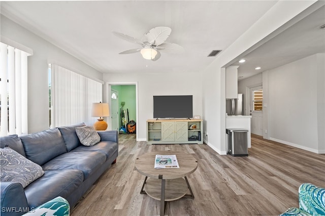 living room with a wealth of natural light, ceiling fan, and light hardwood / wood-style floors