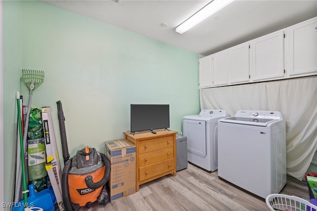 washroom featuring washer and clothes dryer, cabinets, and light wood-type flooring