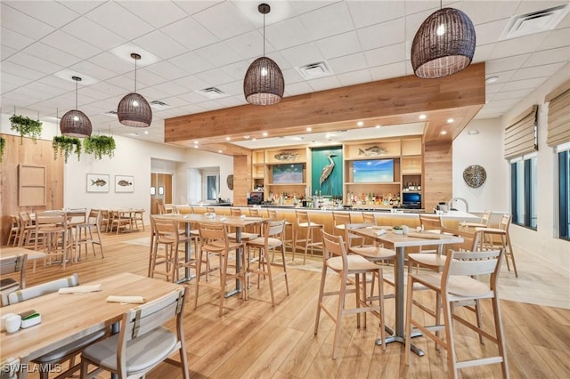 dining space featuring a paneled ceiling and light wood-type flooring