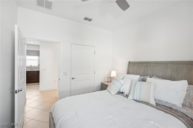 bedroom featuring sink, light tile patterned floors, ceiling fan, and ensuite bath