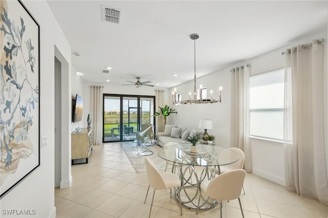 tiled dining room with ceiling fan with notable chandelier