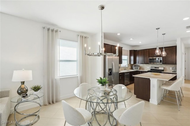 kitchen featuring a kitchen island, sink, hanging light fixtures, dark brown cabinetry, and stainless steel appliances