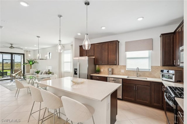 kitchen featuring pendant lighting, sink, a breakfast bar area, appliances with stainless steel finishes, and a center island