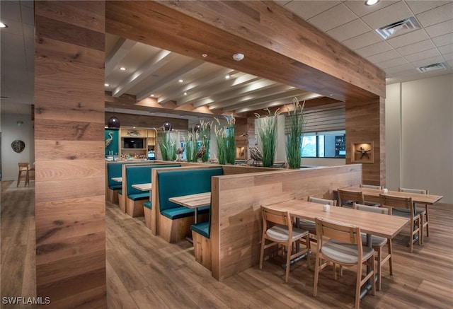 bar with hardwood / wood-style flooring, a paneled ceiling, wooden walls, and beamed ceiling