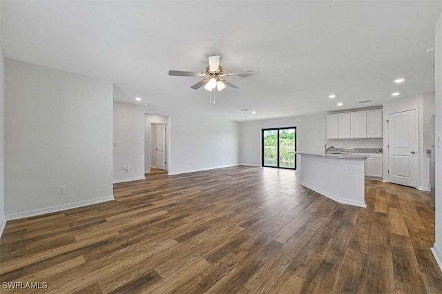 unfurnished living room featuring ceiling fan, sink, and dark hardwood / wood-style floors