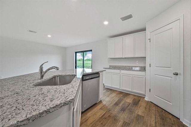 kitchen featuring dark wood-type flooring, white cabinets, sink, stainless steel dishwasher, and light stone counters