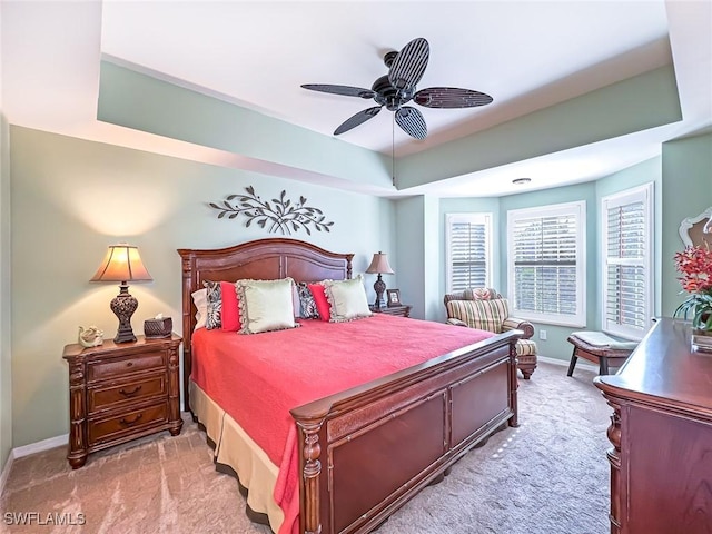 carpeted bedroom with a tray ceiling and ceiling fan