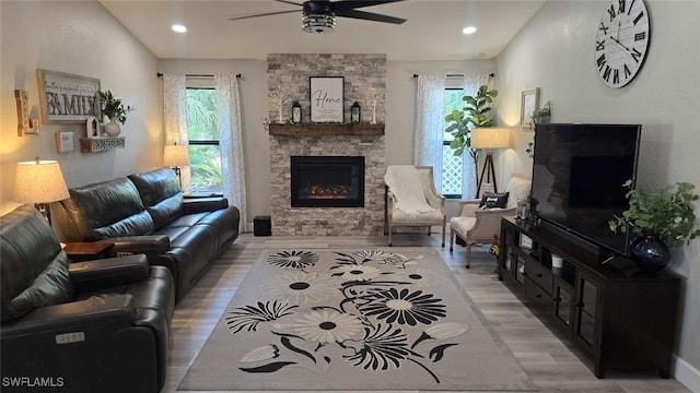 living room featuring a fireplace, ceiling fan, and light hardwood / wood-style flooring