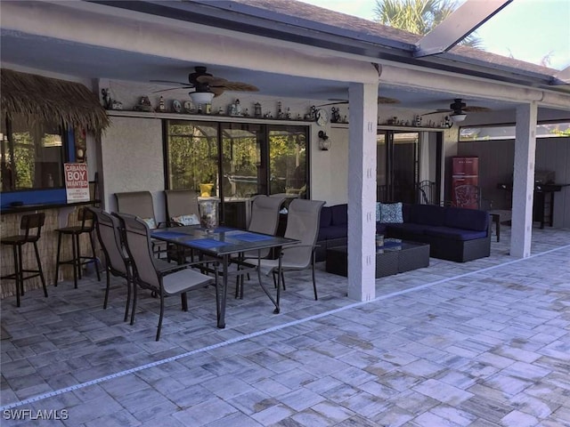 view of patio with grilling area, outdoor lounge area, ceiling fan, and exterior bar