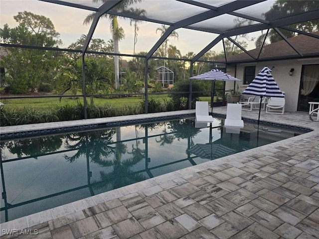 pool at dusk featuring a lanai and a patio