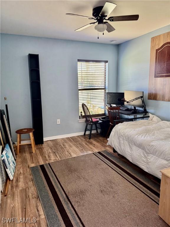 bedroom featuring a ceiling fan, baseboards, and wood finished floors