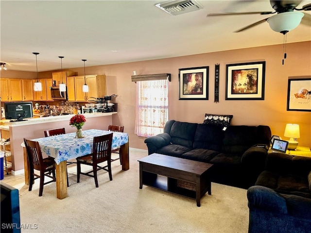 living room featuring light carpet, ceiling fan, and visible vents