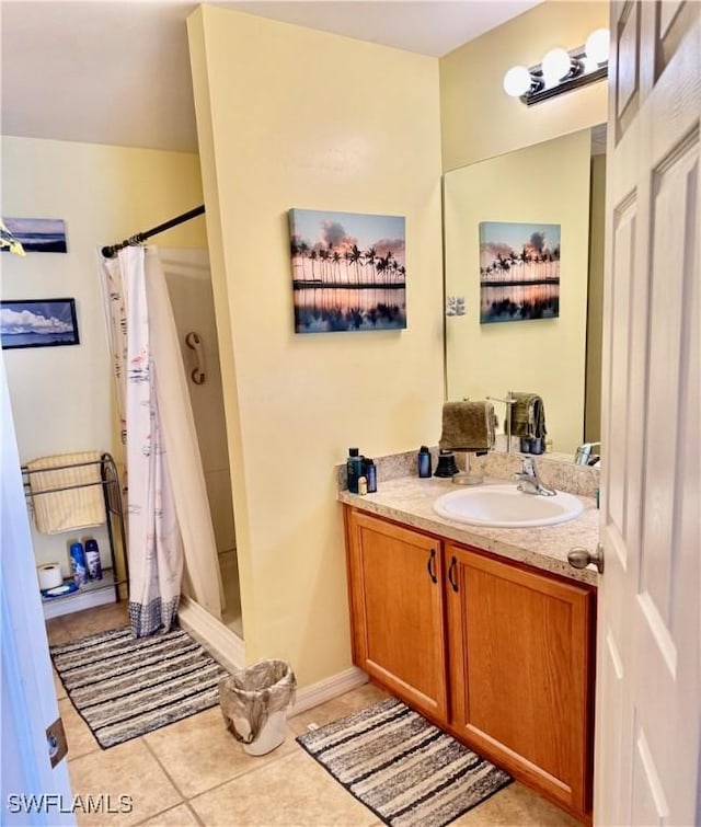 full bathroom with a stall shower, vanity, and tile patterned floors