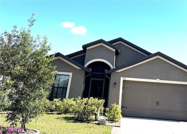 single story home featuring a front yard, an attached garage, driveway, and stucco siding