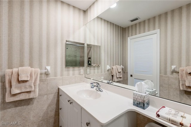 bathroom featuring vanity and tile walls