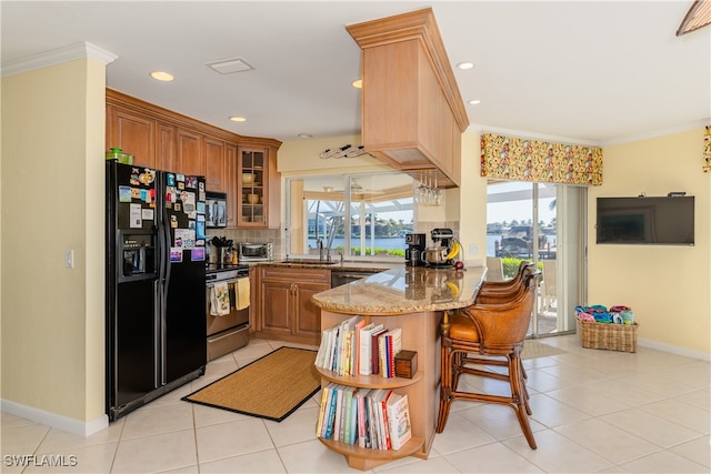 kitchen with kitchen peninsula, appliances with stainless steel finishes, light stone counters, ornamental molding, and light tile patterned floors