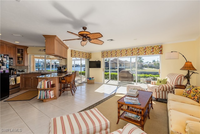 tiled living room with ceiling fan and crown molding