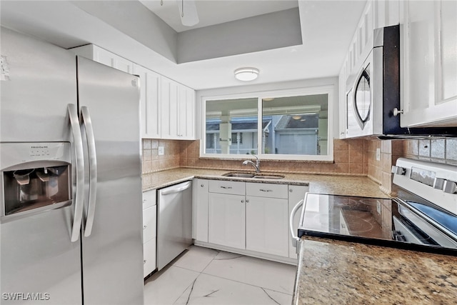 kitchen featuring white cabinetry, stainless steel appliances, backsplash, light stone countertops, and sink