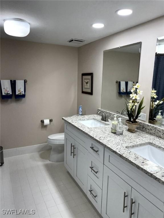 bathroom with visible vents, a sink, toilet, and double vanity