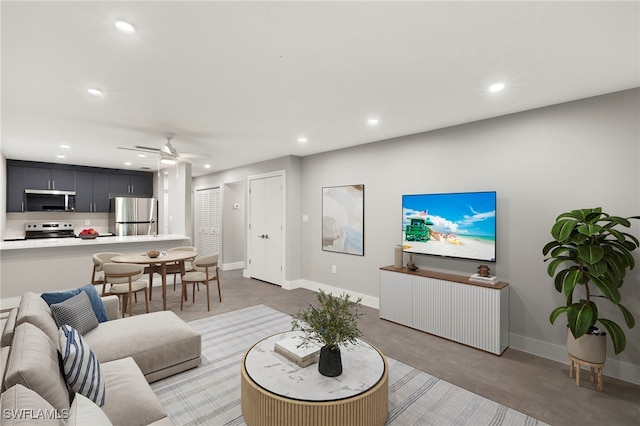 living area featuring finished concrete flooring, baseboards, a ceiling fan, and recessed lighting