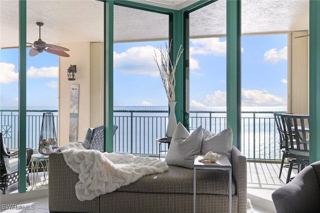 sunroom / solarium featuring plenty of natural light, a ceiling fan, and a water view