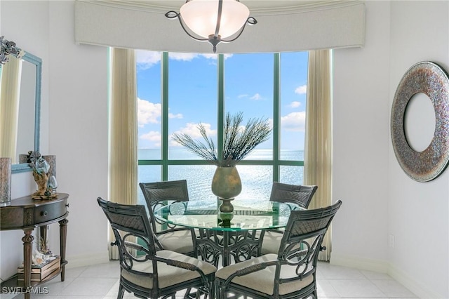 dining area featuring light tile patterned flooring, baseboards, and a water view