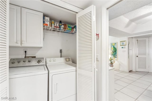 laundry area featuring cabinets, washing machine and dryer, light tile patterned flooring, and a textured ceiling