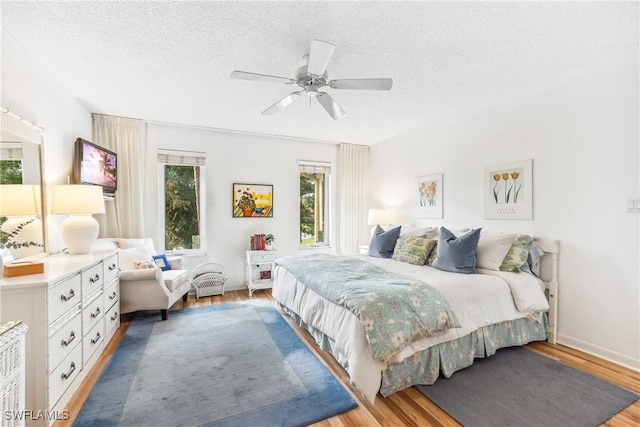 bedroom with hardwood / wood-style floors, a textured ceiling, and ceiling fan