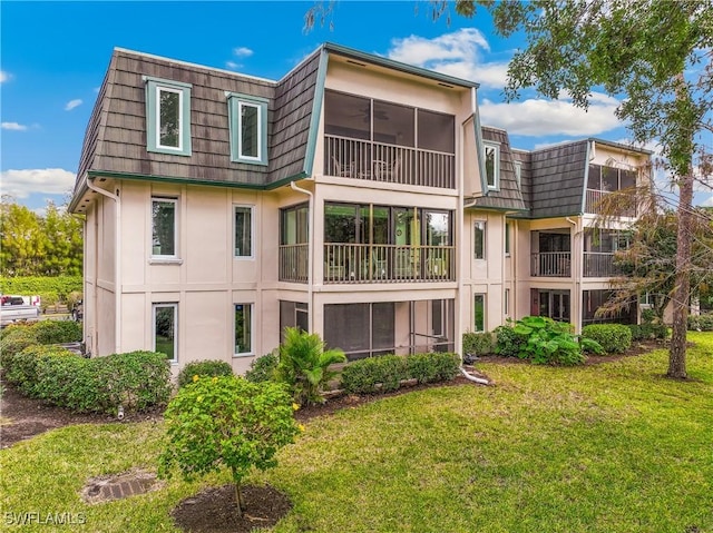 1760 Bald Eagle Dr Unit 506B, Naples, FL 34105 - rear view of house with stucco siding, a lawn, mansard roof, and a sunroom