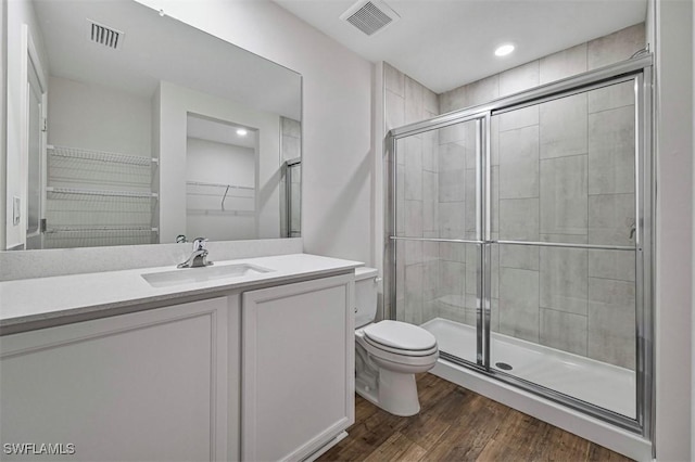 bathroom with hardwood / wood-style floors, vanity, toilet, and a shower with door