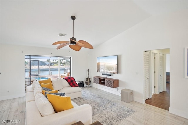 living room with light hardwood / wood-style floors, ceiling fan, and high vaulted ceiling