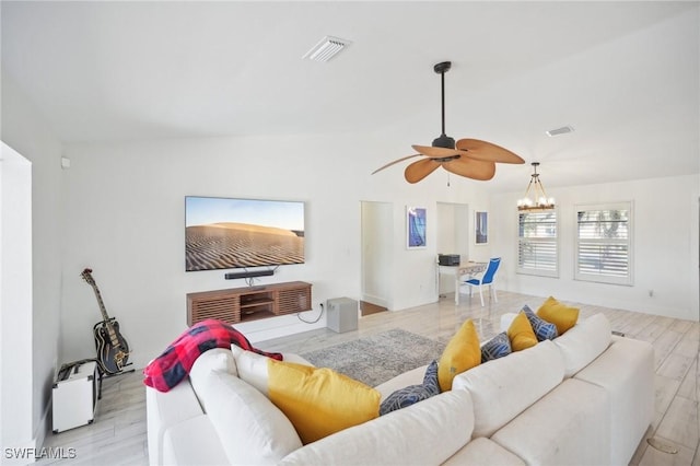 living room featuring ceiling fan with notable chandelier and light hardwood / wood-style floors