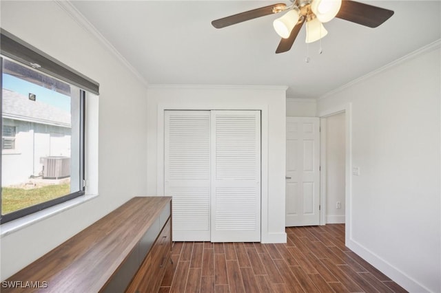 unfurnished bedroom featuring dark wood-style floors, a closet, crown molding, and baseboards