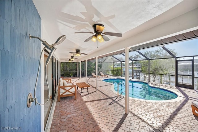 outdoor pool featuring a ceiling fan, glass enclosure, and a patio