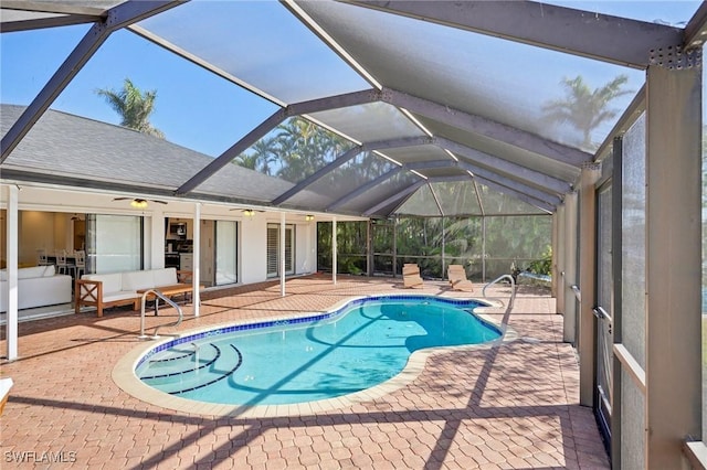 view of pool with ceiling fan, glass enclosure, an outdoor living space, and a patio area