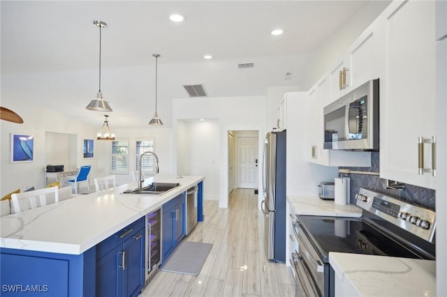 kitchen featuring sink, white cabinets, blue cabinetry, hanging light fixtures, and appliances with stainless steel finishes