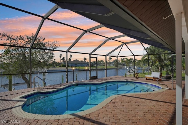 pool at dusk with a lanai, a water view, and a patio area