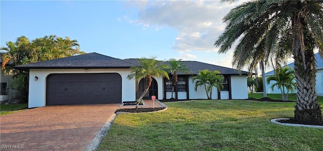 ranch-style house featuring decorative driveway, a garage, a front yard, and stucco siding