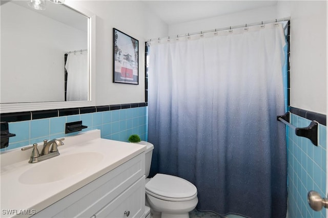 bathroom featuring vanity, toilet, and tile walls