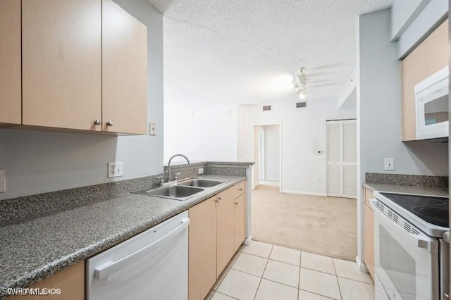 kitchen featuring rail lighting, sink, a textured ceiling, light tile patterned floors, and white appliances