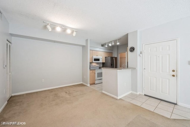 kitchen with light carpet, white appliances, kitchen peninsula, and light brown cabinets