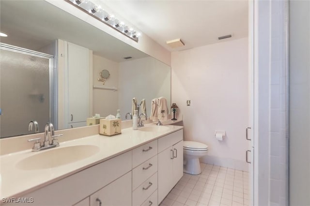 bathroom featuring tile patterned flooring, vanity, a shower with door, and toilet