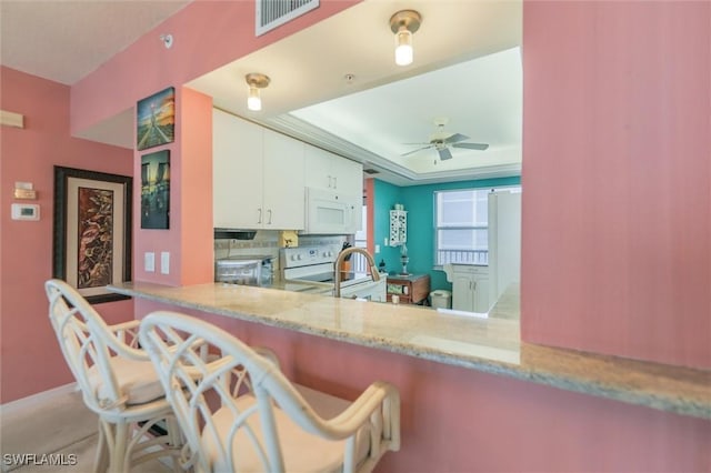 kitchen with kitchen peninsula, backsplash, white appliances, ceiling fan, and white cabinets