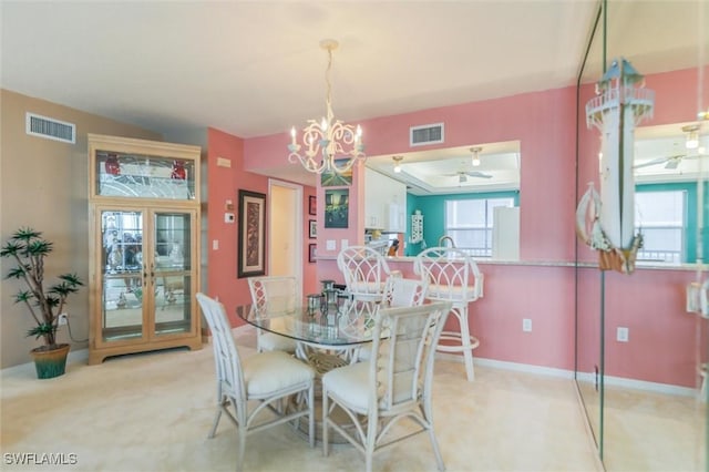 carpeted dining room with ceiling fan with notable chandelier