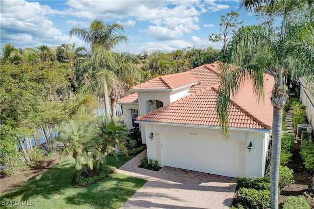 mediterranean / spanish home with central AC unit and a garage