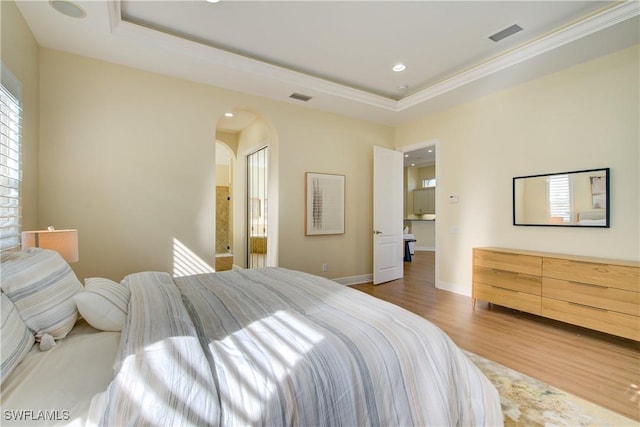 bedroom with a tray ceiling, hardwood / wood-style flooring, and crown molding