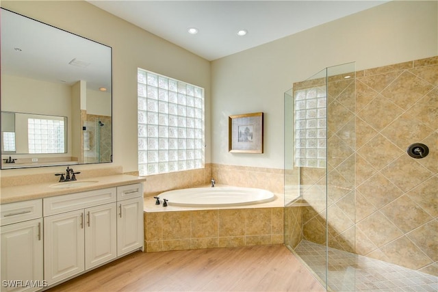 bathroom with hardwood / wood-style floors, vanity, and shower with separate bathtub