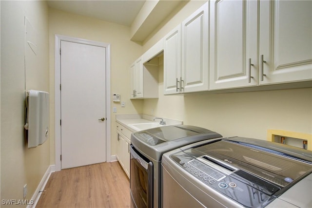 laundry area featuring cabinets, light wood-type flooring, separate washer and dryer, and sink