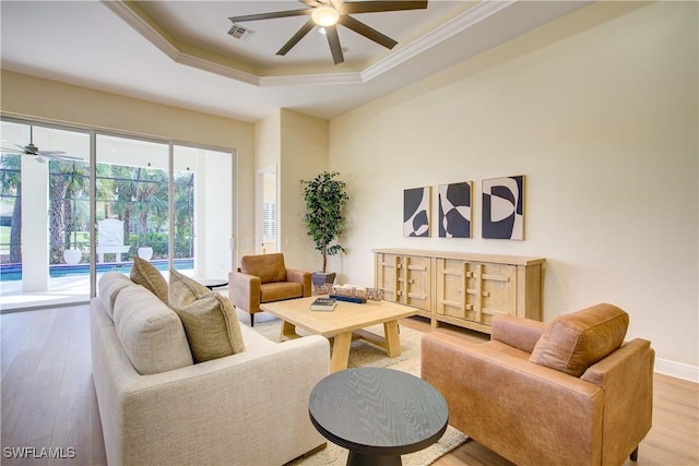 living room featuring a tray ceiling, crown molding, and hardwood / wood-style flooring